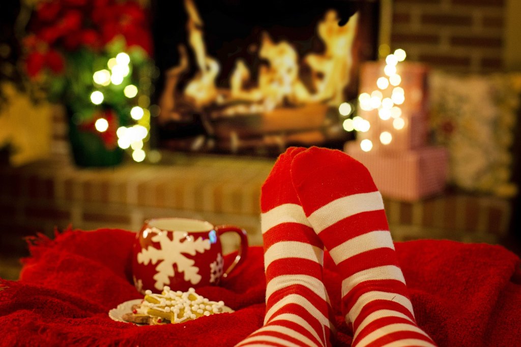 Weihnachtliche rot-weiß gestreifte Socken mit Weihnachtsdeko im Hintergrund.