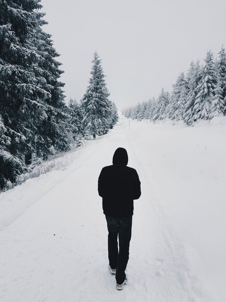 Ein Mann geht einem verschneiten Weg entlang