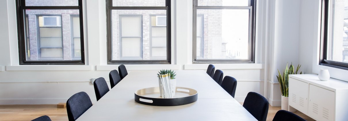 Das Bild zeigt ein leeres Besprechungszimmer mit Tisch und Sesseln.