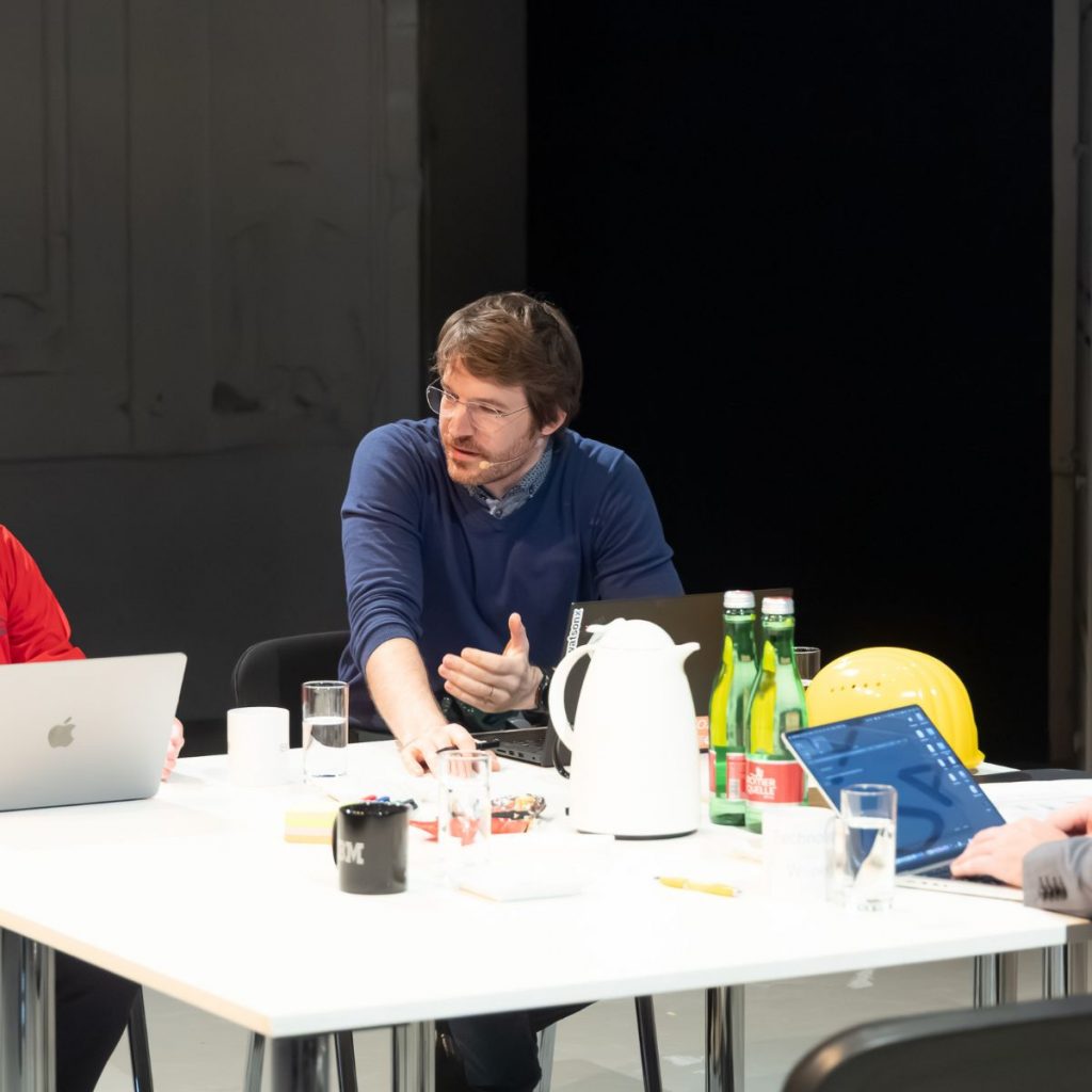 Data-Governance-Theaterstück mit vier Personen auf einer Bühne, die über widersprüchliche Daten diskutieren