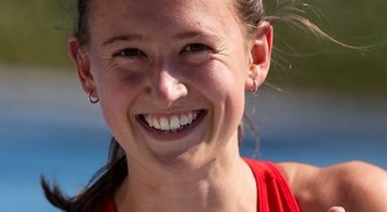 Das Bild zeigt Anja Dlauhy in ihrem Leichtathletikdress mit glücklichem Gesichtsausdruck und Daumen-Hoch Handhaltung.